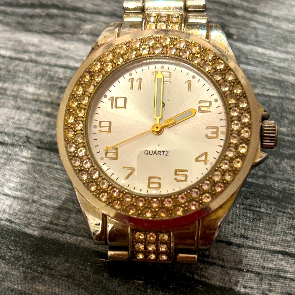 Quarts watch with silver and gold bracelet and on face of it has rhinestones